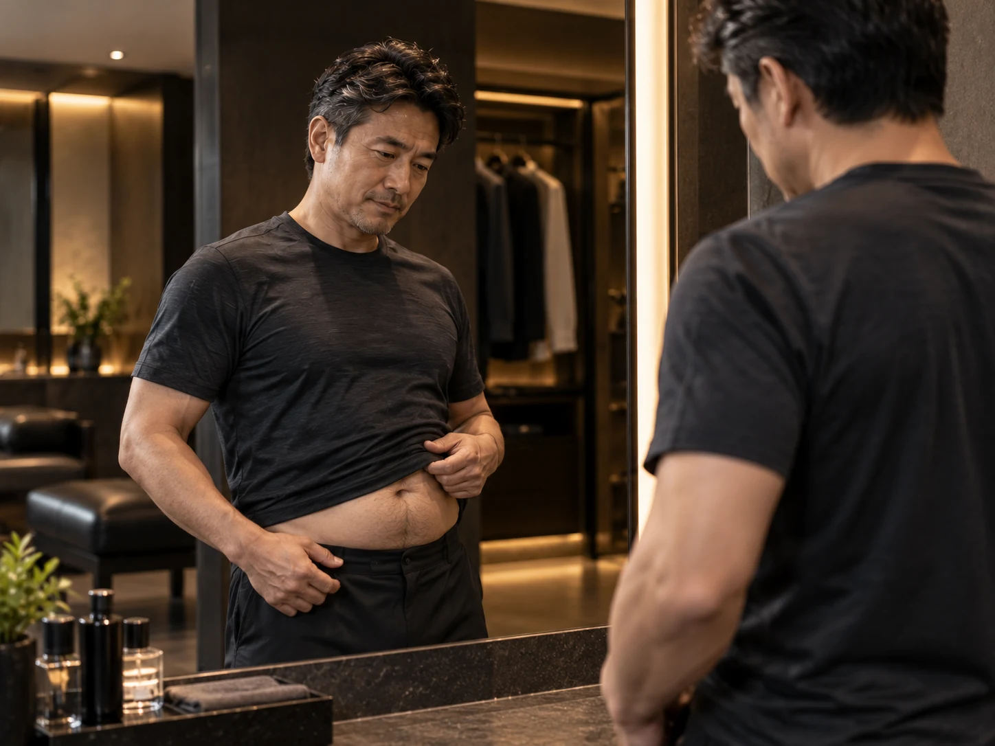 鏡の前でお腹まわりの変化が気になっている40代男性